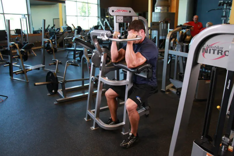 Preacher curl aan de machine, eindpositie