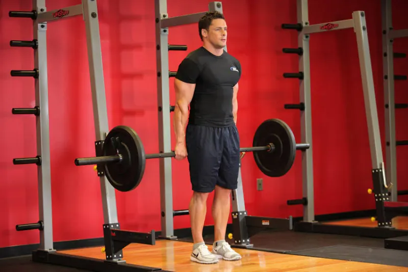 Shrugs met barbell achter je rug